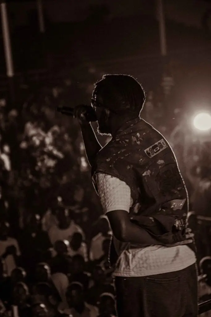 J12 MONEY video: a man holding a microphone in front of a crowd