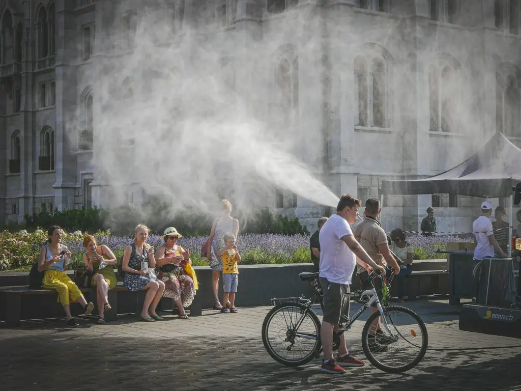 France Heatwave Deaths: People cooling off from mist spray on a hot day